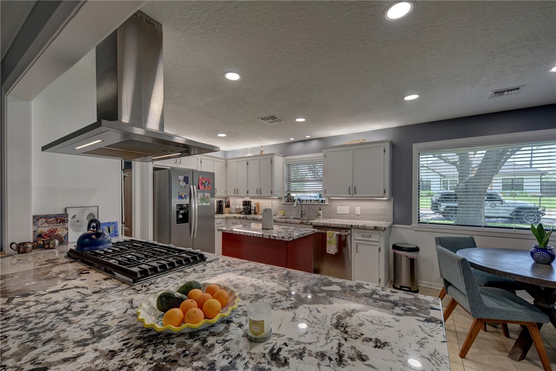 1600 Pecan Street Brenham, TX 77833 - Photo 23 of 33 Gas cook top, exhaust hood, stainless steel appliances, natural lighting, a sink, recessed lighting, and tasteful backsplash