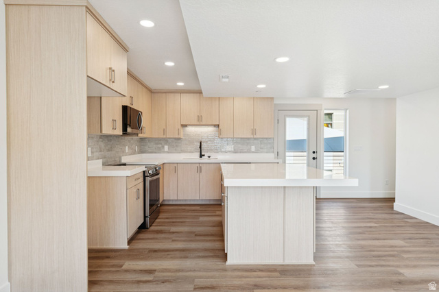 252 North Main Street Bountiful, UT 84010 - Photo 6 of 34 Kitchen featuring light wood finish cabinetry, a center island, stainless steel appliances, light wood-type flooring, and decorative backsplash