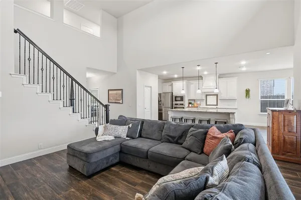 a living room with furniture kitchen view and a wooden floor