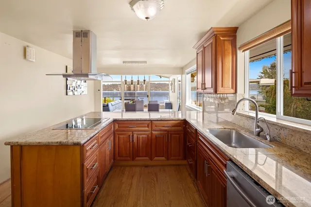 a large kitchen with granite countertop a sink and dishwasher a oven with wooden cabinets