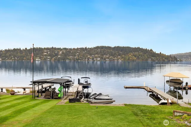 a view of a lake with a yard and a wooden fence