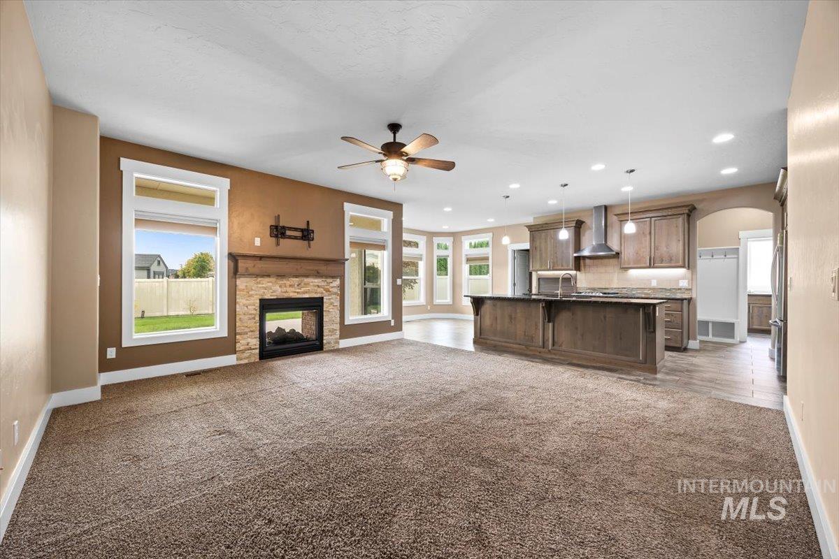 13557 Signorello Street Caldwell, ID 83607 - Photo 10 of 30 Unfurnished living room featuring dark carpet, a fireplace, arched walkways, a ceiling fan, and recessed lighting