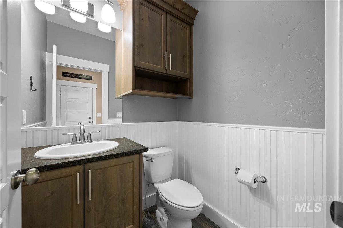 13557 Signorello Street Caldwell, ID 83607 - Photo 17 of 30 Half bathroom with vanity, a wainscoted wall, and a textured wall