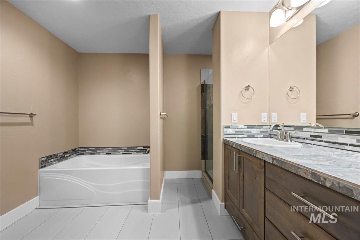13557 Signorello Street Caldwell, ID 83607 - Photo 20 of 30 Full bathroom with vanity, a garden tub, light tile patterned flooring, and a stall shower