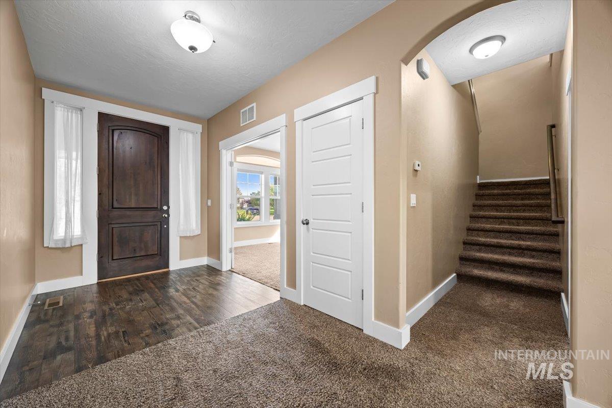13557 Signorello Street Caldwell, ID 83607 - Photo 5 of 30 Entryway featuring dark carpet, a textured ceiling, arched walkways, and stairs