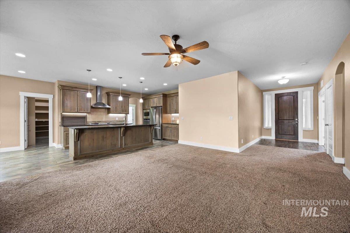 13557 Signorello Street Caldwell, ID 83607 - Photo 30 of 30 Kitchen featuring open floor plan, dark countertops, dark carpet, an island with sink, and pendant lighting