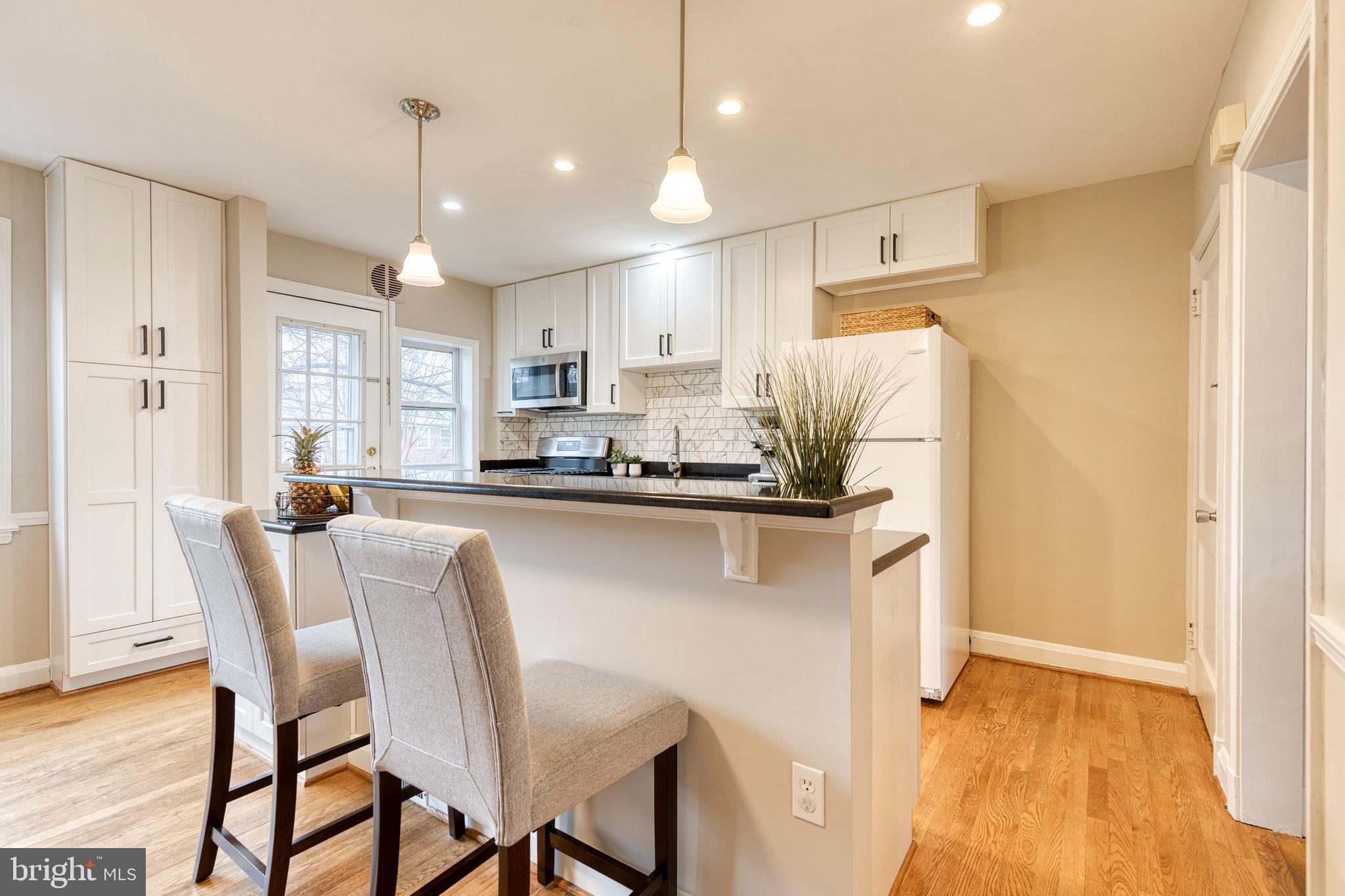 31 Regester Avenue Baltimore, MD 21212 - Photo 17 of 38 a kitchen with stainless steel appliances granite countertop a refrigerator a stove a sink dishwasher and a dining table with wooden floor
