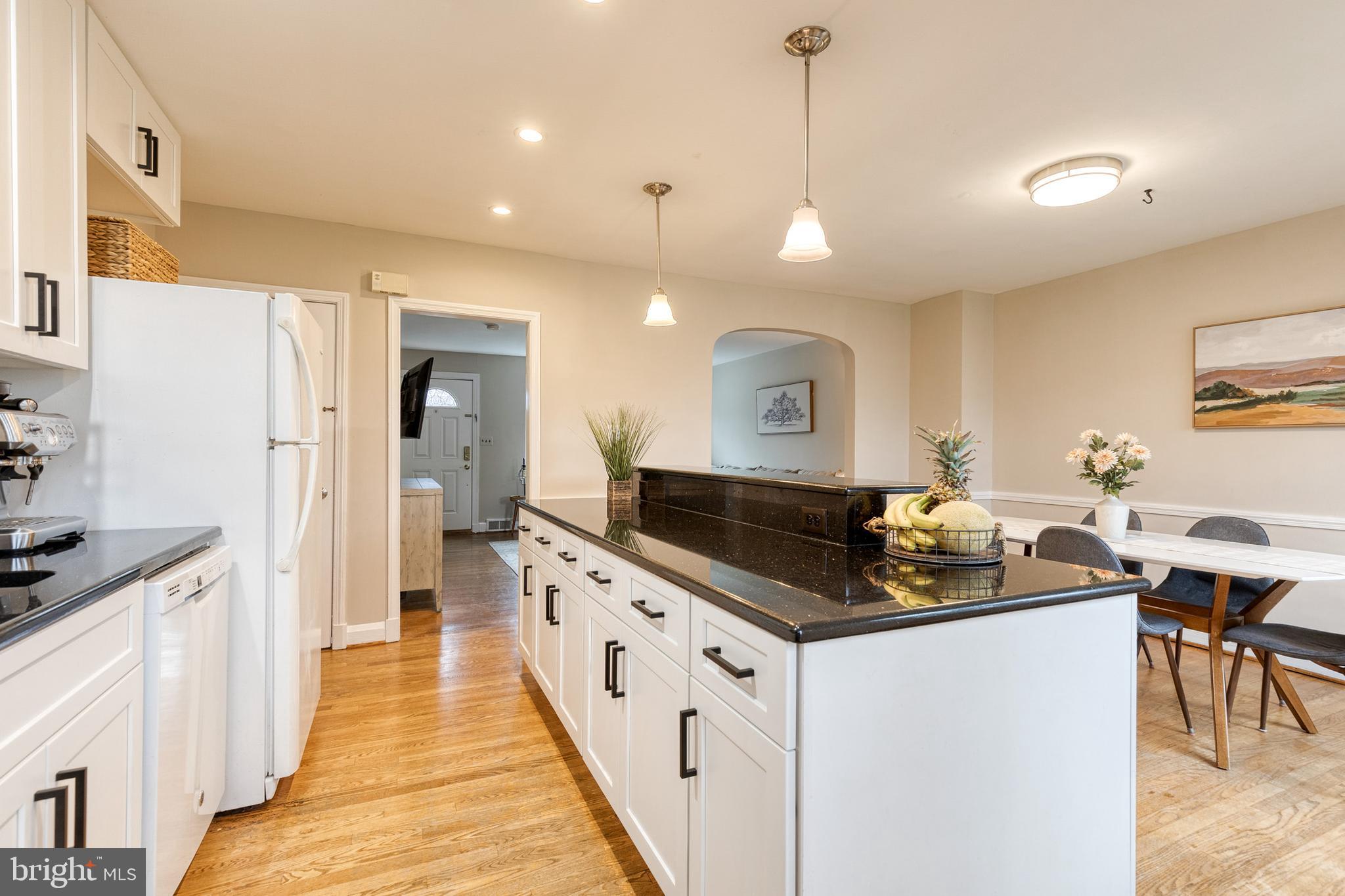 31 Regester Avenue Baltimore, MD 21212 - Photo 21 of 38 a kitchen with granite countertop a stove a sink a refrigerator and white cabinets with wooden floor