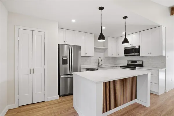a kitchen with stainless steel appliances granite countertop a refrigerator a sink dishwasher a oven and a stove with wooden floor