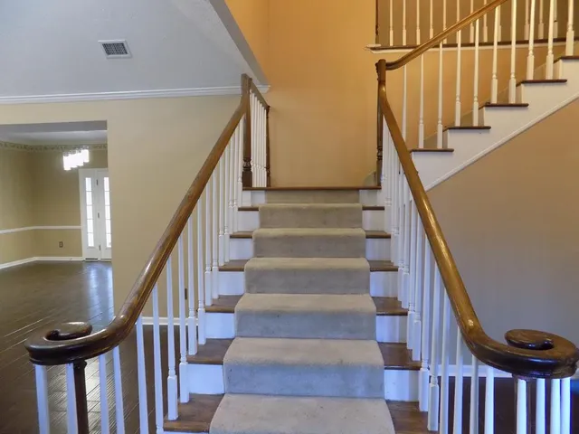 a view of staircase with lots of frames on wall and wooden floor