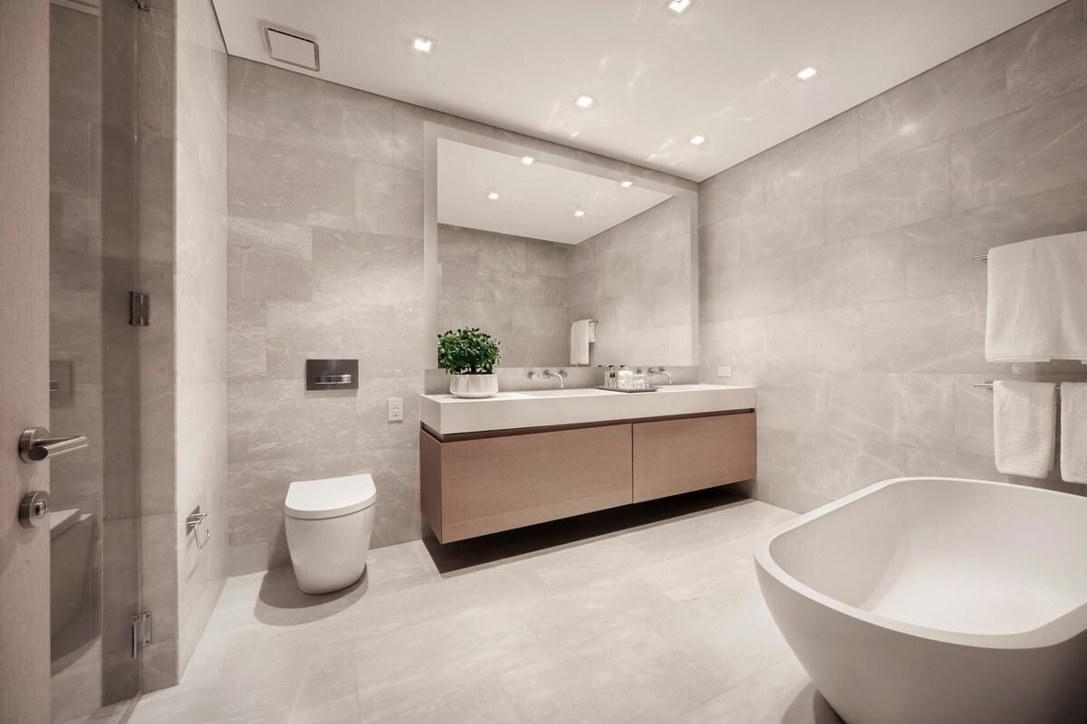 49 Chambers Street, Unit 16C Manhattan, NY 10007 - Photo 4 of 19 a bathroom with a white tub sink vanity mirror and toilet