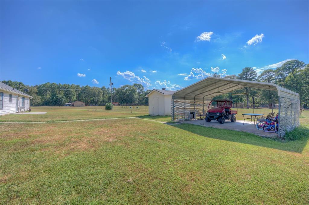 8835 Sebastian Road Keithville, LA 71047 - Photo 5 of 21 Expansive grassy yard with a detached storage shed and a metal carport