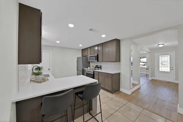 a large kitchen with stainless steel appliances a sink a stove and cabinets