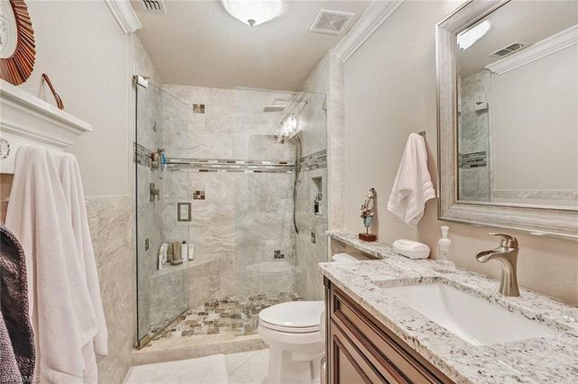 a bathroom with a granite countertop sink toilet and shower