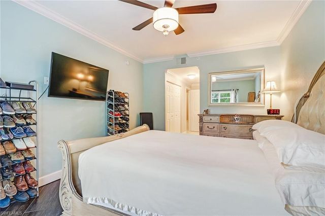 a bedroom with a bed a flat screen tv and a chandelier