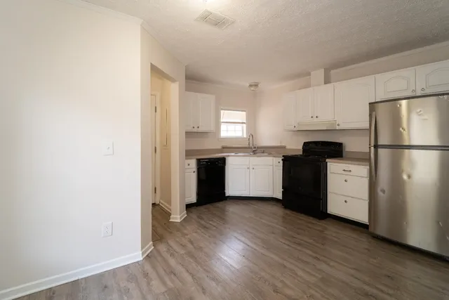 a kitchen with a refrigerator a sink and dishwasher with wooden floor