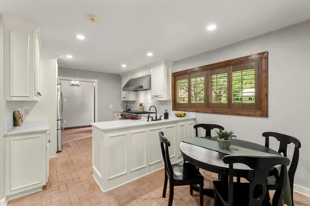 a kitchen with stainless steel appliances granite countertop a stove a sink a refrigerator with a dining table and chairs