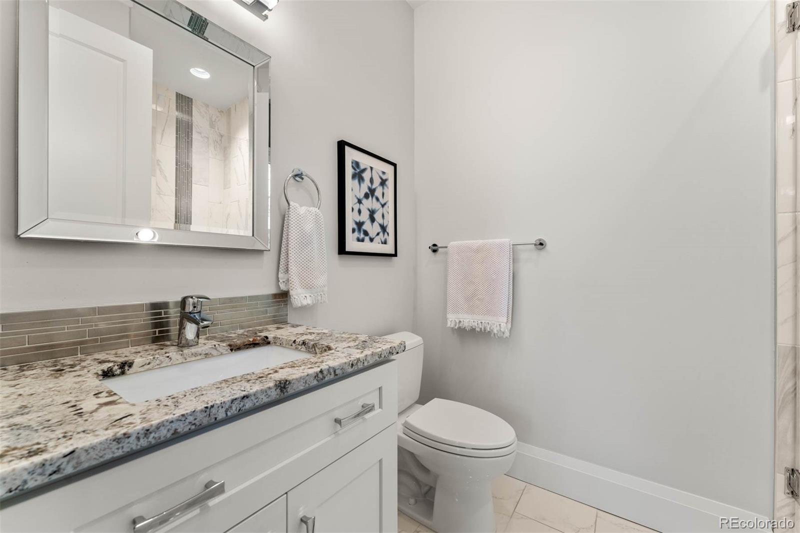 1645 South Cook Street Denver, CO 80210 - Photo 25 of 48 a bathroom with a granite countertop sink a toilet and mirror