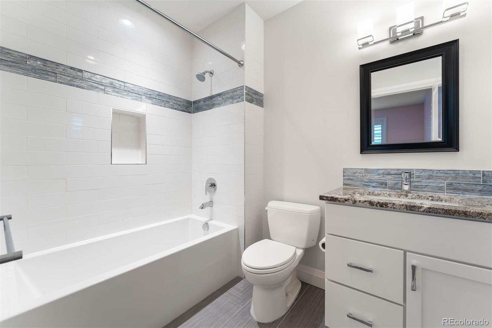 1645 South Cook Street Denver, CO 80210 - Photo 39 of 48 a bathroom with a toilet a sink a mirror and a bathtub