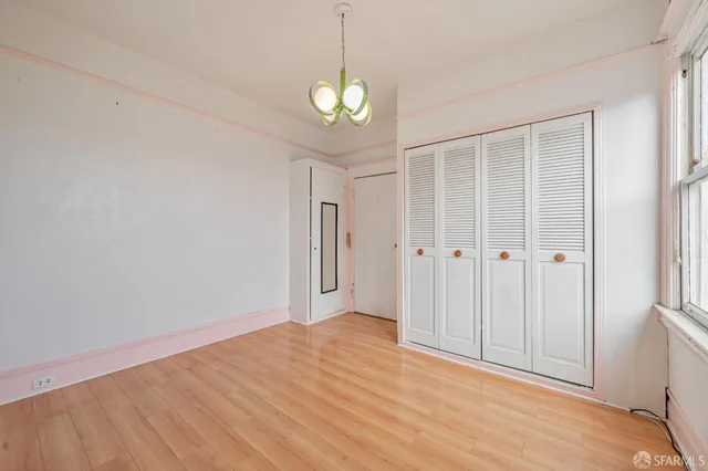 a view of an empty room with window and wooden floor
