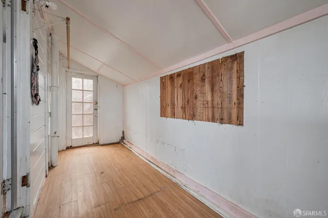 a view of an empty room with window and wooden floor