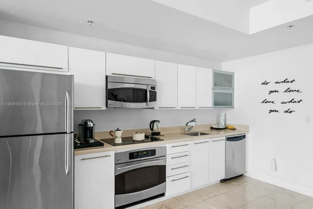 a kitchen with stainless steel appliances white cabinets white stove a sink and a refrigerator