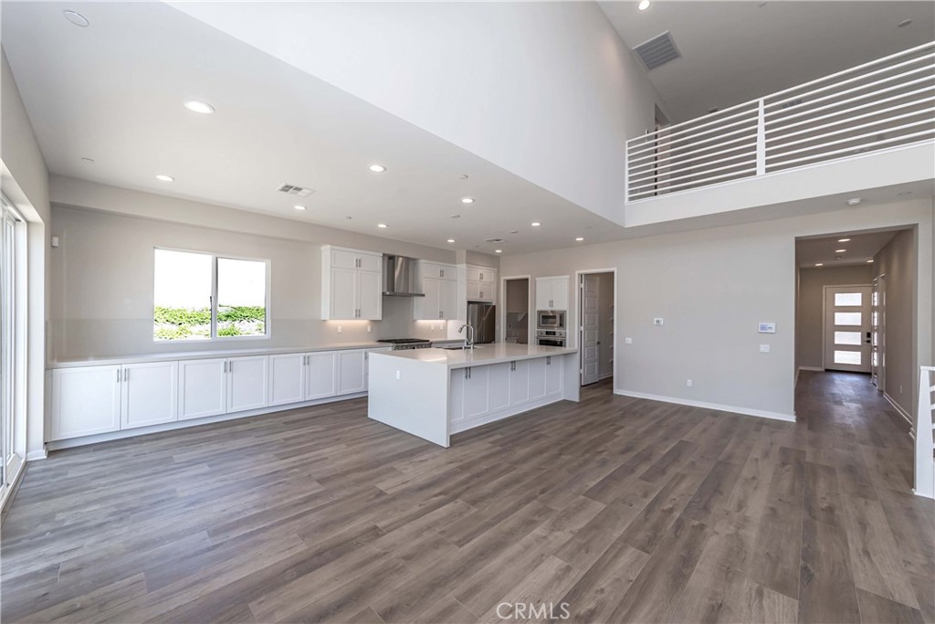 6521 Canyon Oaks Drive Simi Valley, CA 93063 - Photo 5 of 39 a large white kitchen with kitchen island a sink wooden floor and a refrigerator