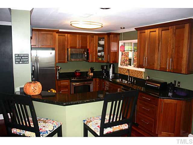 5009 Raintree Court Raleigh, NC 27609 - Photo 4 of 23 a kitchen with stainless steel appliances wooden cabinets a stove top oven a sink and dishwasher