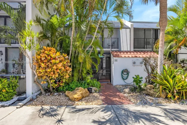 a view of a house with plants and large trees