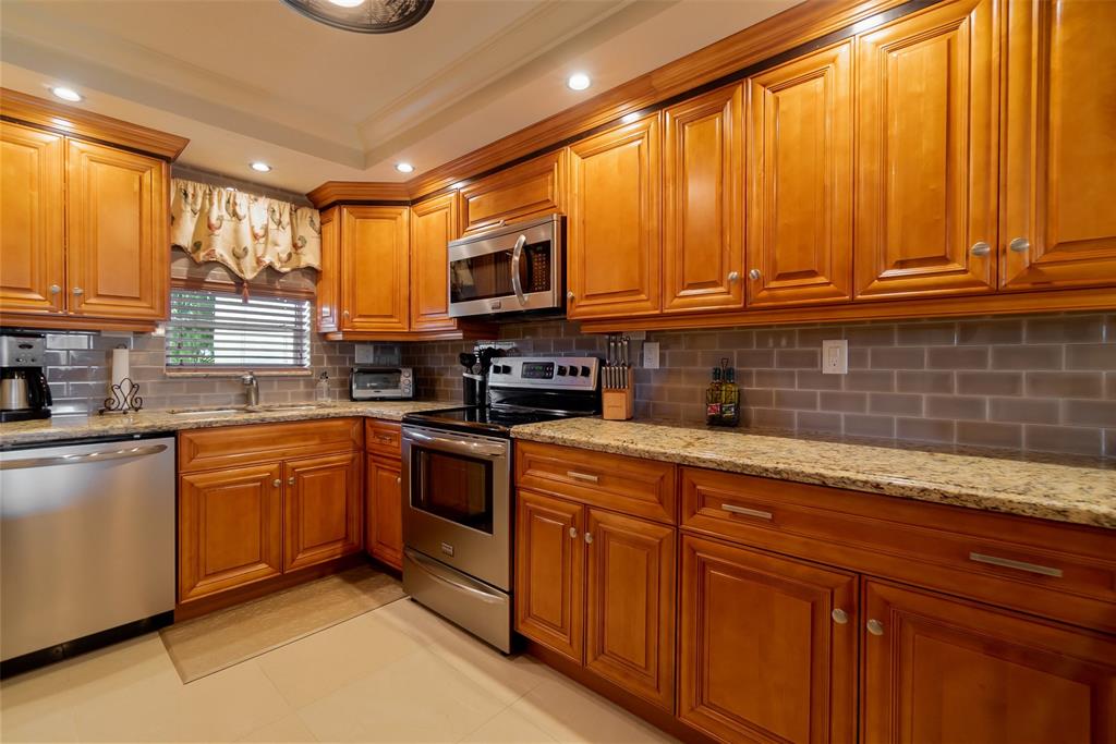 a kitchen with stainless steel appliances granite countertop a sink a stove cabinets and a microwave