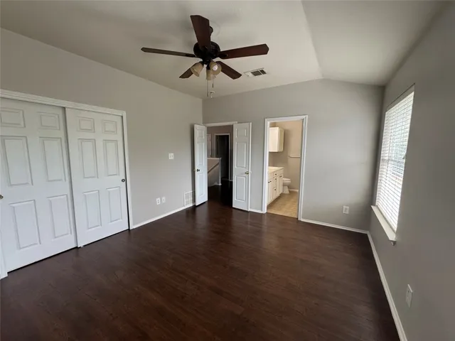 an empty room with wooden floor fan and windows