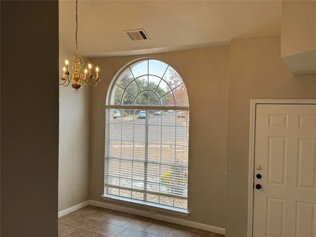 an empty room with chandelier outdoor view and entryway
