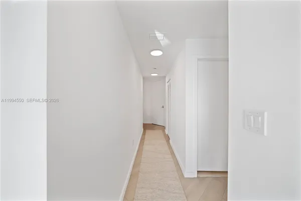 a view of a hallway with wooden floor and a door