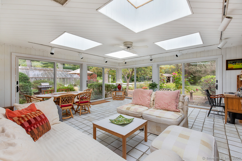71 Beecher Road Woodbridge, CT 06525 - Photo 11 of 32 Bright sunroom with garden views surrounded by expansive sliding glass doors and multiple skylights, the room is filled with natural light and offers panoramic views of the landscaped grounds.