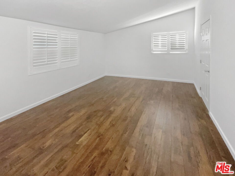 17530 Devonshire Street Northridge, CA 91325 - Photo 9 of 39 an empty room with wooden floor and windows