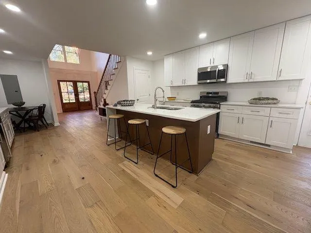 a kitchen with stainless steel appliances granite countertop a stove a sink dishwasher and a refrigerator with wooden floor