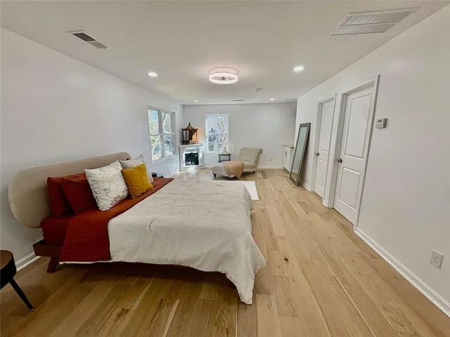 a spacious bedroom with a bed and wooden floor