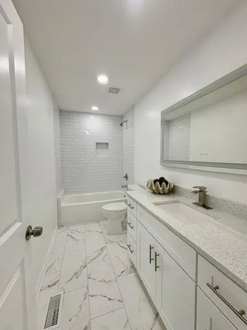 a spacious bathroom with a granite countertop sink a toilet and a shower
