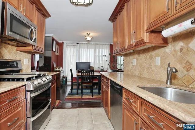 a kitchen with stainless steel appliances granite countertop a stove top oven a sink dishwasher and cabinets with wooden floor