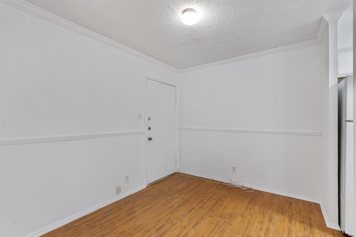 4103 Speedway, Unit 202 Austin, TX 78751 - Photo 2 of 13 Empty room featuring a textured ceiling, light wood-type flooring, and ornamental molding