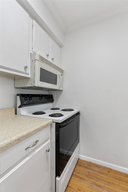 4103 Speedway, Unit 202 Austin, TX 78751 - Photo 5 of 13 Kitchen with range with electric cooktop, light countertops, white cabinetry, white microwave, and crown molding