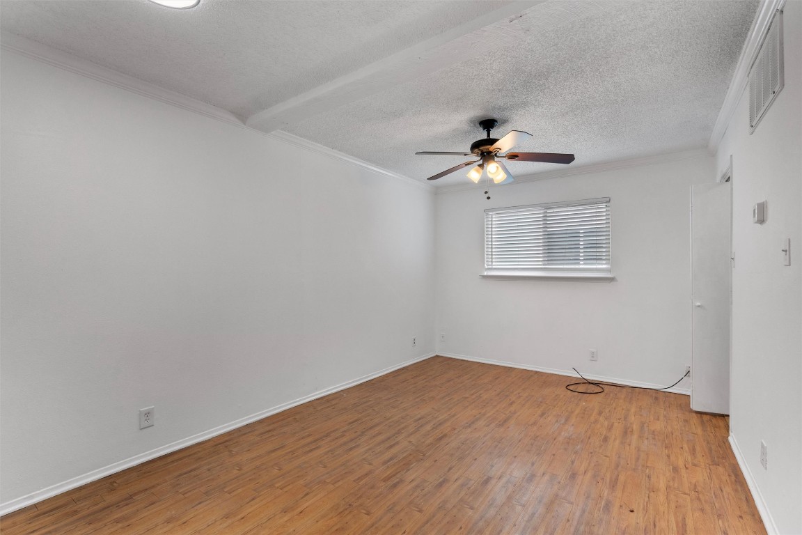 4103 Speedway, Unit 202 Austin, TX 78751 - Photo 7 of 13 Spare room with a textured ceiling, light wood-style floors, ornamental molding, and a ceiling fan