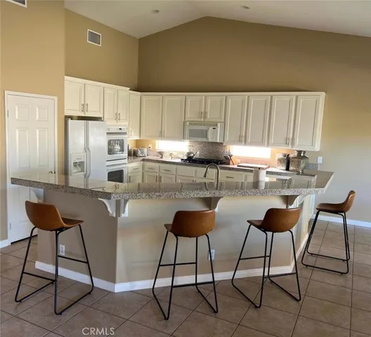 a kitchen with stainless steel appliances kitchen island granite countertop a table chairs and a refrigerator