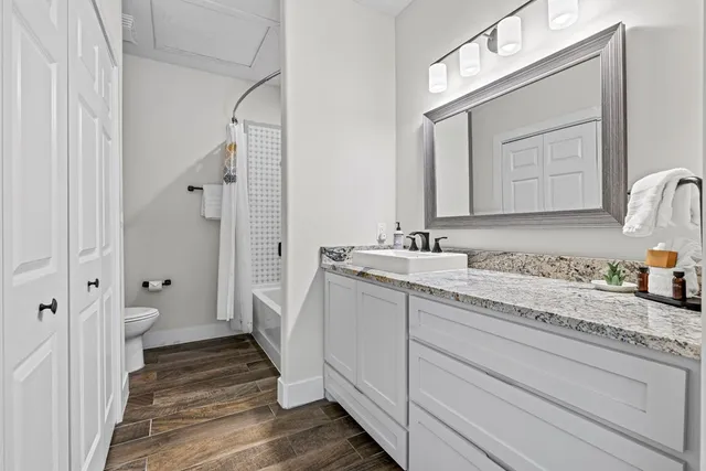 a bathroom with a granite countertop sink mirror and a toilet