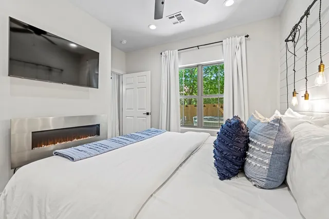 a bedroom with a bed a flat screen tv and a large window