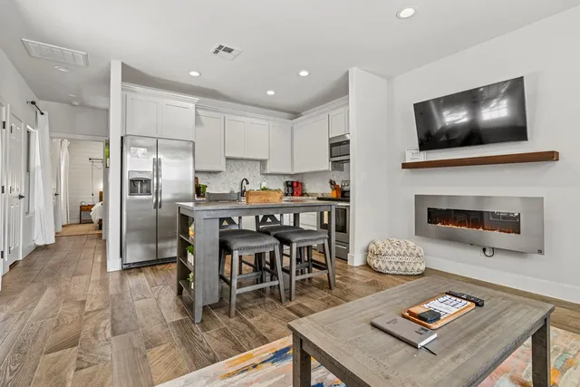 a living room with stainless steel appliances kitchen island granite countertop furniture and a fireplace