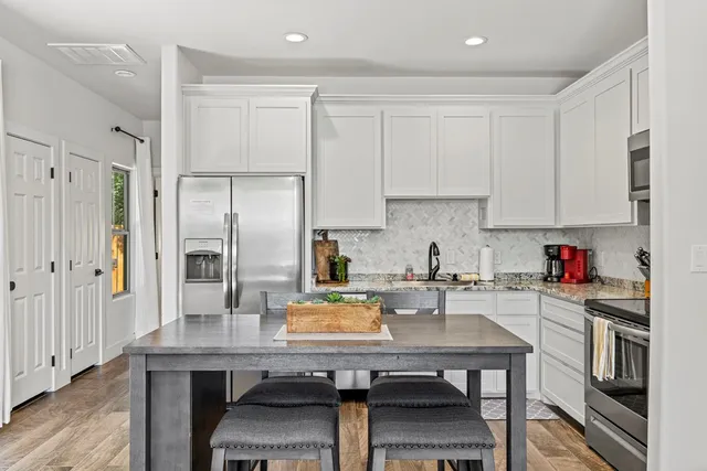 a kitchen with a refrigerator a stove a sink and white cabinets with wooden floor