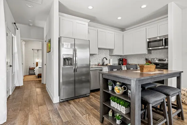 a kitchen with granite countertop a wooden floor and stainless steel appliances