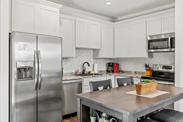 a kitchen with stainless steel appliances granite countertop a refrigerator a sink a stove and a refrigerator