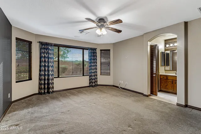 an empty room with chandelier fan and windows